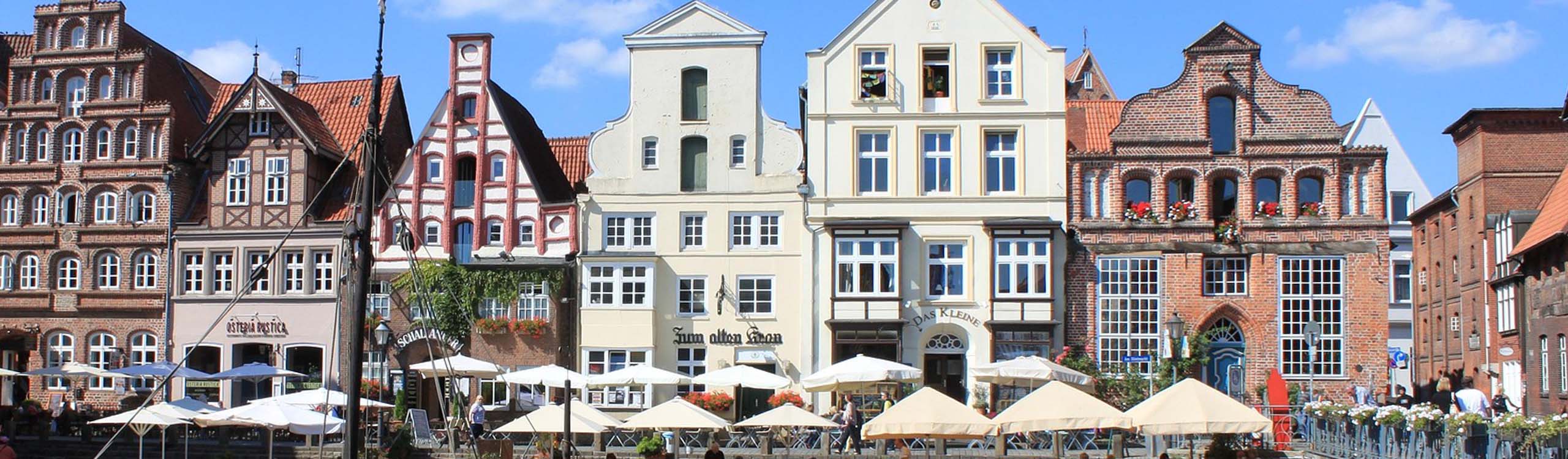 der Lüneburger Stint mit Giebelhäusern und Terrassen mit Sonnenschirmen entlang der Ilmenau